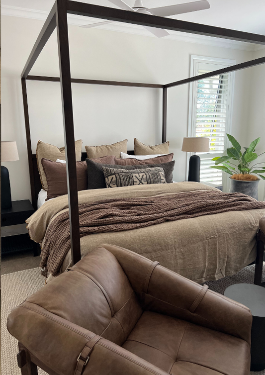 Bedroom with a four-poster bed and brown leather chair.