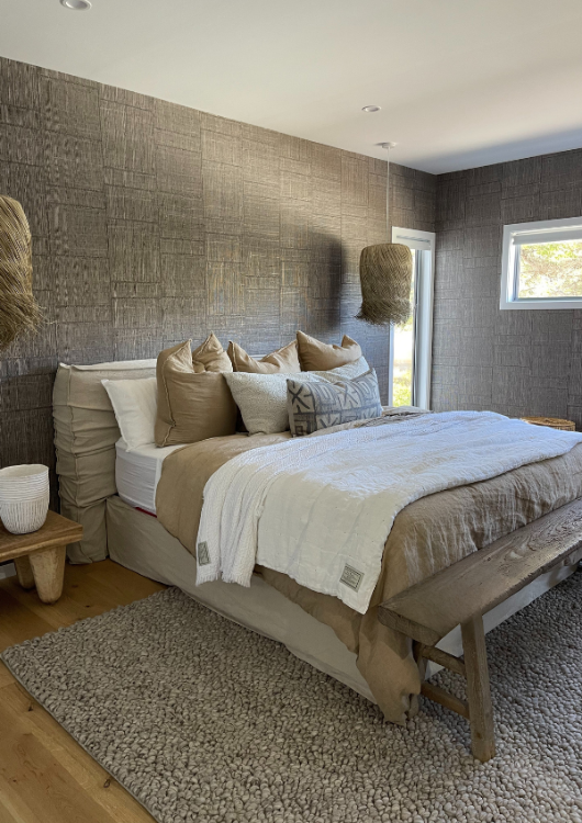 Interior styling modern bedroom with textured wallpaper, rug and layered bed linen