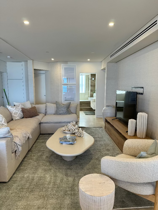 Modern living room with beige sofa, coffee table, and armchair. Bungalow Interiors Gold Coast