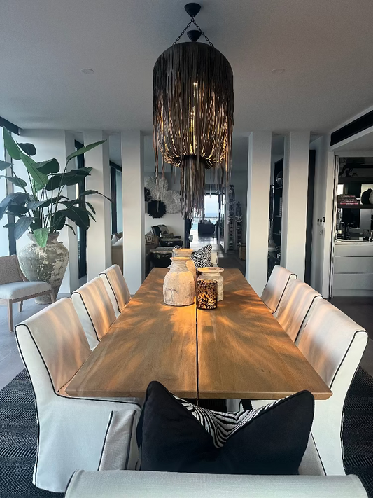 Main Beach Dining room with a wooden table and white chairs, featuring a modern chandelier. Bungalow Interiors Design + Home Styling