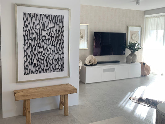 Modern living room with a wooden bench, abstract art, and a television.