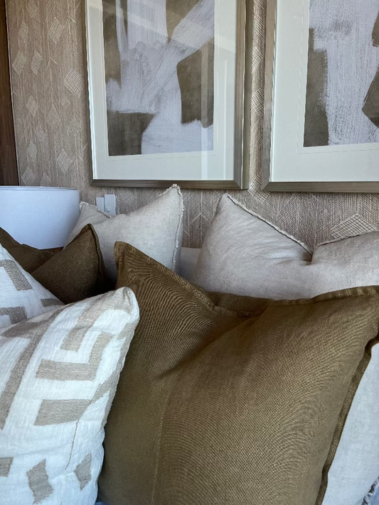 Decorative pillows on a sofa with abstract art in the background. Bungalow Home Interiors Design Studio