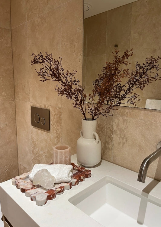 Bathroom sink area with decorative elements including a vase with branches and a tray.