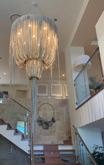 Luxurious chandelier hanging in a home interior with staircase and wall decor. Bungalow Interiors Design & Styling, Gold coast