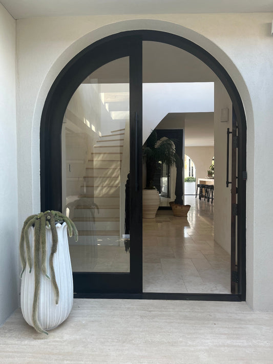 Modern interior design with a black framed archway leading to a living room.