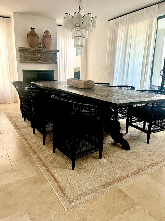 Dining room with a large black dining table and chairs on a beige rug. Bungalow Home Interiors Designer Gold Coast