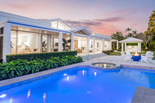 Luxurious house with a pool and outdoor seating area at dusk. Bungalow Interiors Home Styling Sanctuary Cove