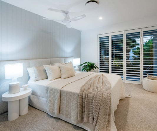 Modern bedroom with a bed, side tables, and large windows. Home styling Bungalow Interiors Gold Coast