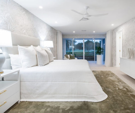 Modern bedroom with white bedding and decor, featuring a large window view. Home styling Bungalow Interiors Gold Coast