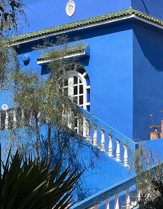 Blue building with white balcony and green roof against a clear blue sky