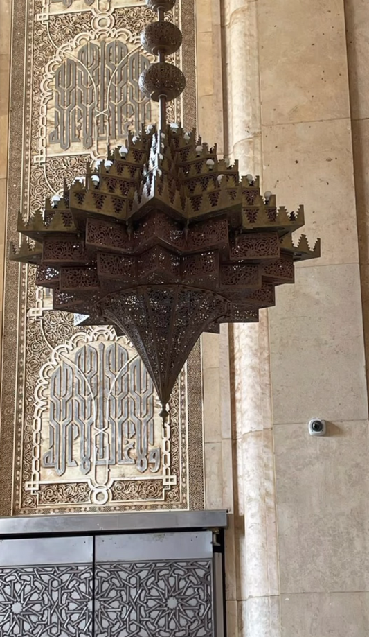 Decorative chandelier hanging in a room with ornate wall patterns