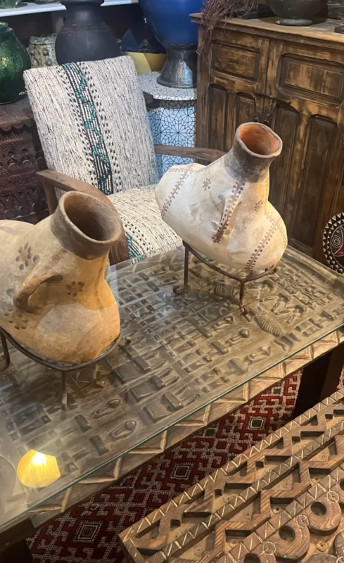 Two ceramic vases on a glass table with a textured surface and decorative rug underneath.