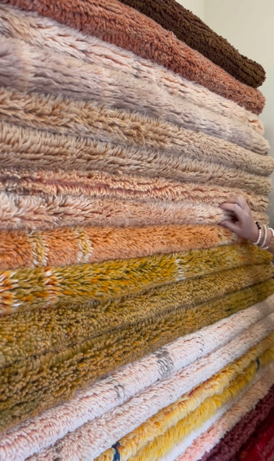 Stack of colorful textured fabrics with a hand reaching out.