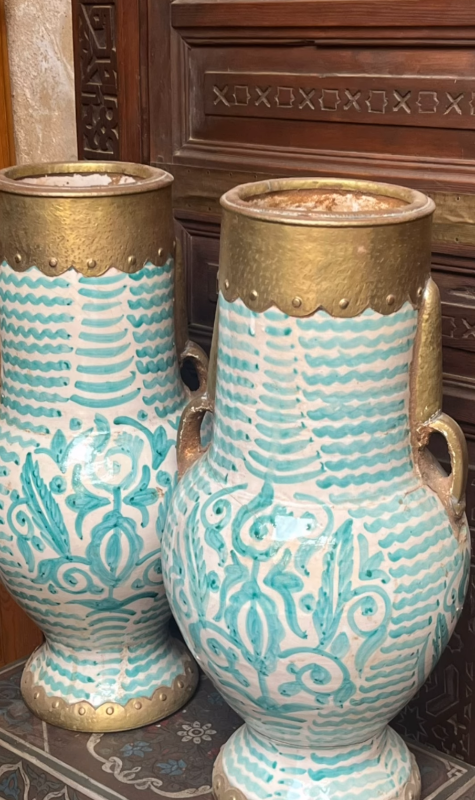 Two decorative vases with turquoise patterns and gold accents on a wooden surface.