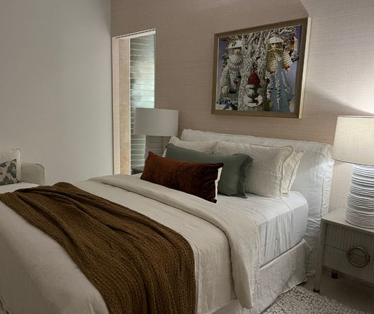 Neatly made bed with decorative pillows and a framed picture on the wall in a bedroom setting.