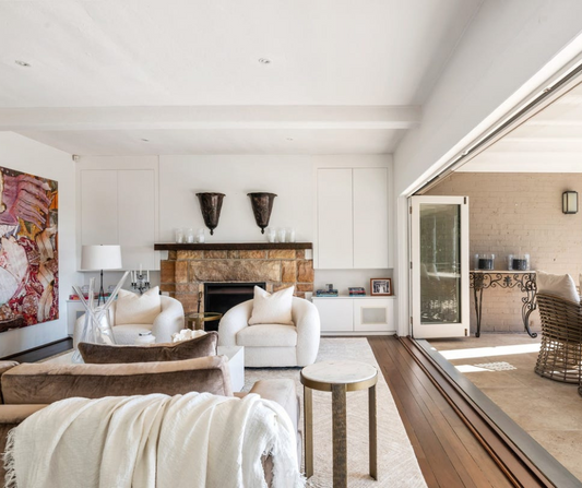 Modern living room with white furniture, artwork, and a fireplace.