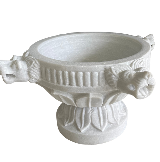 A white marble planter with a detailed lion's face design.