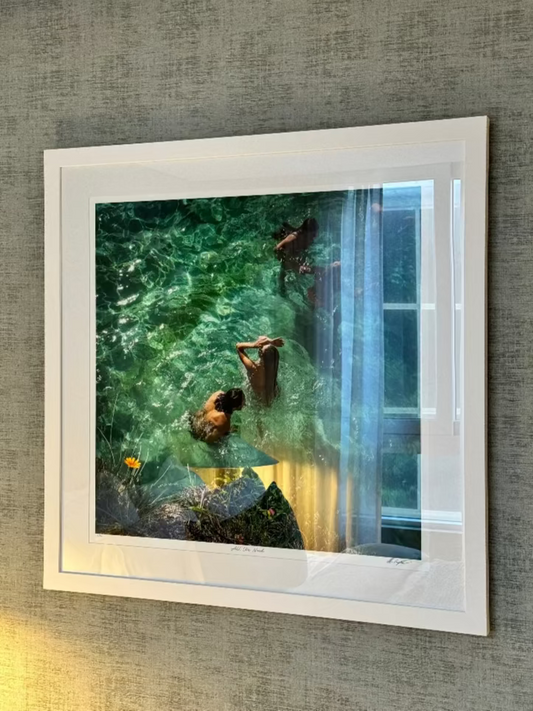 Framed photograph of two people in a pool with a white frame on a textured wall.  Bungalow Interiors Design Gold Coast