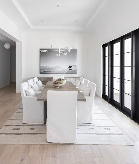 Modern dining room with white chairs, a long table, and a large window.  Bungalow Interior Design, Gold Coast