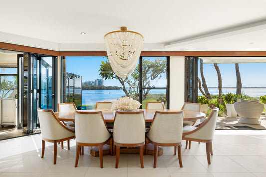 Dining room with a large table and chairs, featuring a chandelier and a view of the ocean. Bungalow Interiors Home Styling, Gold Coast