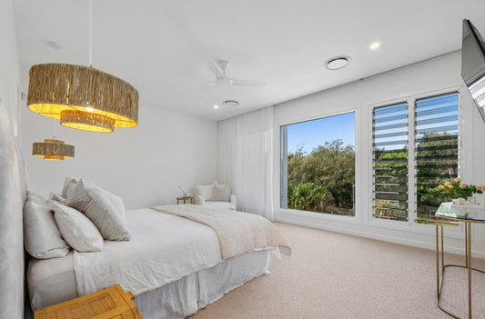 Modern bedroom with large windows, bed, and decorative elements.