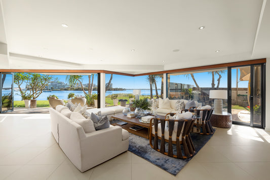 Modern living room with white furniture and large windows overlooking a waterfront. Bungalow Interiors home styling, Gold Coast