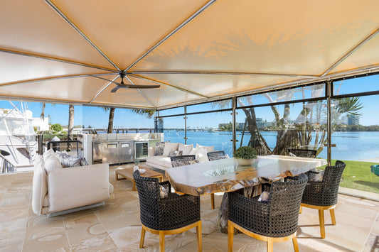 Outdoor patio area with furniture and a view of water and palm trees. Bungalow Interiors home styling, Gold Coast