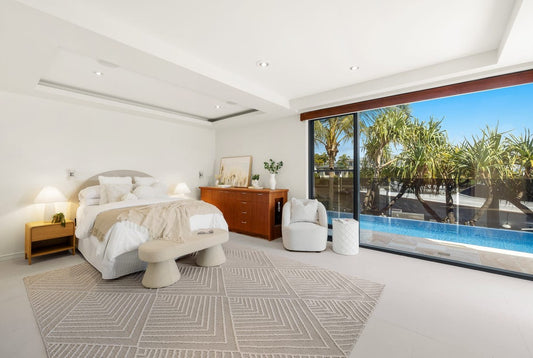 Modern bedroom with a large window view of trees and water. Bungalow Interiors home styling, Gold Coast
