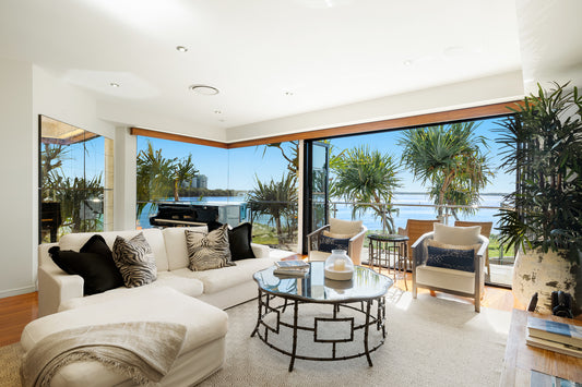 Modern living room with white furniture, large windows, and a view of the ocean.  Bungalow Interiors home styling, Gold Coast